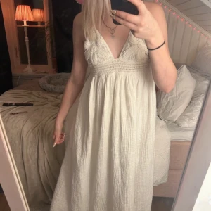 Vit långklänning med spetsdetaljer - Säljer en vacker vit långklänning med spetsdetaljer och v-ringning. Klänningen har en romantisk känsla och är perfekt för sommarens tillställningar. Den är ärmlös och har en luftig passform som ger en bekväm och elegant look.skulle vara väldigt fint om man har en lite större byst en vad jag har 