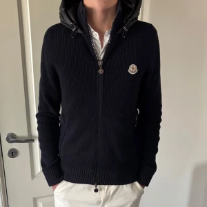 Moncler Tricot Hooded Down Cardigan  - Moncler Tricot Hooded Down Cardigan Skick 8,5/10  Självklart äkta, kan lösa bevis pm Ganska ovanlig modell riktigt fet Size 4 (Large), sitter som size 3 (Medium) Öppen för bytesförslag. 2 pyttesmå hål på ryggen som inte syns när luvan är nere. En lagning på fickan
