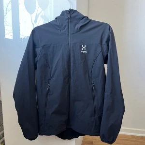 Svart vindjacka från Haglöfs - Säljer en svart vindjacka från Haglöfs i storlek S för dam. Jackan har en praktisk huva och dragkedja framtill.  Inga skador. Pris kan diskuteras :) Samt vid eventuella frågor hör av er. 