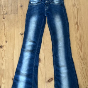 Blå bootcut jeans från Cheap Monday 26/32 - Säljer ett par klassiska blå bootcut jeans från Cheap Monday med snygga slitningar och utställda ben. Jeansen har normal passform och är tillverkade i denim med en liten del stretch för extra komfort.