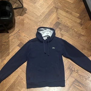 Lacoste hoodie - Mörkblå Lacoste hoodie i storlek S men är ganska liten i storlek. Den är i bra skick.