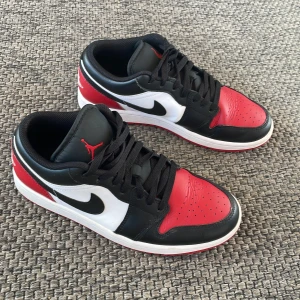 Nike Jordan Low - Säljer ett par Nike Air Jordans Low med klassisk färgkombination i svart, rött och vitt. De är köpta i USA och jag har ingen box men skorna är nästan oanvända. Nya kostar mellan 1500-1700kr