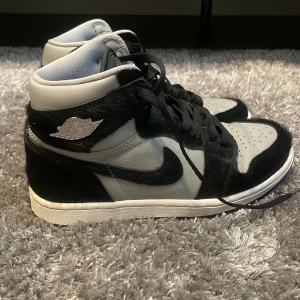 Nike Air Jordans svart och grå - Säljer ett par Nike Air Jordans i svart och grått med högt skaft. Skorna har svart snörning, vit sula och klassisk vinge-logo på sidan. Materialmix med både skinn och syntet, samt rund tå. Perfekta för dig som gillar streetstyle.