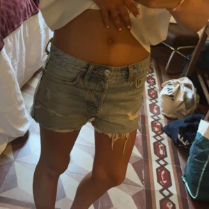 Jeansshorts med slitningar - Snygga jeansshorts med slitningar och fransiga kanter. Perfekta för en avslappnad sommarlook. De har en klassisk blå färg och en lågmidjad passform.