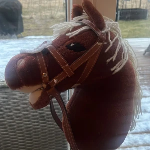 Brun käpphäst med vit man - Charmig brun käpphäst med vit man och detaljerad brunt träns. Perfekt för lek och äventyr. Hästen har en mjuk päls och realistiska detaljer som gör den till en favorit hos barn.