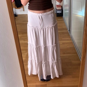 Vit långkjol från BikBok - Säljer en vit långkjol från BikBok i storlek XS. Kjolen har flera volanger och ett knytband i midjan för justerbar passform. Perfekt för en avslappnad och stilren look. Säljer då den inte kommer till användning. Nypris 400kr. Priset kan diskuteras. 💞💞