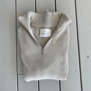 Beige stickad tröja från Jack and Jones - Säljer en stilren beige stickad tröja från J.Lindeberg. Tröjan har en dragkedja vid halsen och är ribbad för en snygg look. Perfekt för kyligare dagar! Priset är inte hugget i sten så här gärna av er.
