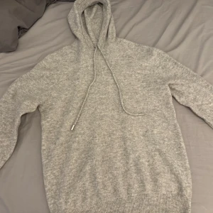 Grå hoodie cashmere - Säljer en stilren grå hoodie cashmere med justerbar huva och ribbade muddar. Perfekt för en avslappnad look. Passar bra till både jeans och träningsbyxor.