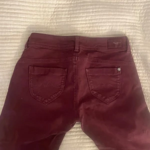 Vinröda byxor från Pepe Jeans - Snygga vinröda byxor från Pepe Jeans. Byxorna har snygga detaljer som en dragkedja vid ena framfickan och design på bakficorna. Dom är slim i modellen. 