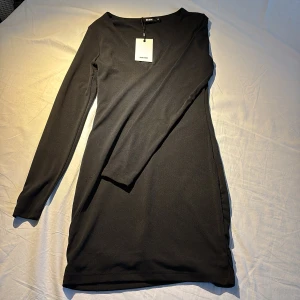 Svart klänning från BIK BOK - Snygg svart klänning från BIK BOK i storlek XS. Klänningen har en v-ringad design och långa ärmar, perfekt för en stilren look. Materialet är mjukt och stretchigt för en bekväm passform.