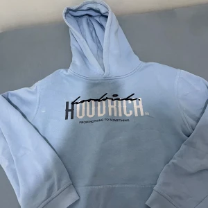 Ljusblå hoodie från Hoodrich - Säljer en snygg ljusblå hoodie från Hoodrich med tryck på bröstet och ryggen. Hoodien har en klassisk design med en stor huva och långa ärmar. Perfekt för en avslappnad stil. 🩵