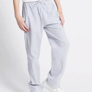 Randiga byxor med snörning - Snygga och bekväma randiga byxor i ljusblått och vitt. Byxorna har en loose passform och är utrustade med snörning i midjan för en justerbar passform. Perfekta för en avslappnad pyjamas