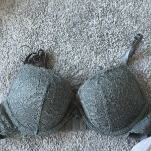 Grön spets-bh - Säljer en grön bh med vacker spetsdetalj. Bh:n har justerbara axelband och en klassisk knäppning bak. Kommer ifrån HM och är i storlek 75B, endast provad. 
