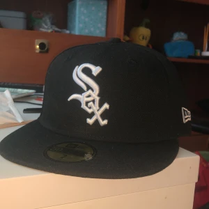 Svart keps med vit logga från New Era - Säljer min sox keps pga av att jag köpte fel storlek, köpte för typ 540 men säljer för 500, haft på mig den 1 gång finns inga skador på den.