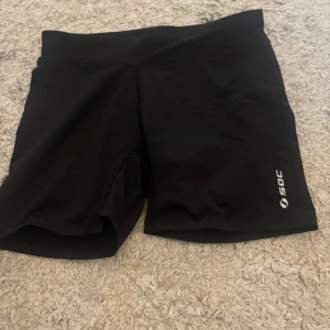 Svarta träningsshorts från SOC - Säljer ett par svarta träningsshorts från SOC. De är perfekta för träning och har en bekväm passform. Shortsen är tillverkade i ett syntetmaterial som andas och håller dig sval under intensiva pass. Storlek 158-164