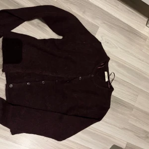 Vinröd kofta från Gina Tricot - Säljer en vinröd kofta från Gina Tricot i premiumkvalitet. Aldrig använt. Koftan har långa ärmar och knappar framtill. Perfekt för kyligare dagar och ger en stilren look.