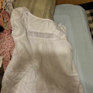 Vit tröja från Lindex - Säljer en vit tröja från Lindex i storlek S. Klänningen har spetsdetaljer och är perfekt för sommarens varma dagar. Den är ärmlös och har en luftig passform.