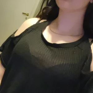 Svart ribbad topp från Zara - Säljer en svart ribbad topp från Zara med offshoulder-design. Perfekt för en stilren look. Toppen har en modern och trendig stil som passar till många tillfällen.