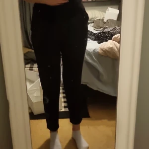 Svarta kostymbyxor från Vero Moda - Snygga svarta kostymbyxor från Vero Moda i en klassisk design. Byxorna har en normal passform och är perfekta för en stilren look. De är tillverkade i ett bekvämt material och har en elastisk midja för extra komfort.