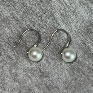 Silverfärgade örhängen med pärlor - Säljer ett par stilrena örhängen i silverfärg med vita pärlor. Vet tyvärr inte vad det är för material, men de är i fint skick. 