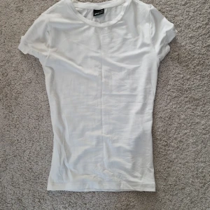 Vit t-shirt  - En skims-liknande vit t-shirt från gina tricot med rund halsringning och korta ärmar. Perfekt basplagg i garderoben, tillverkad i mjuk bomull för en bekväm känsla. Enkel och stilren design som passar till det mesta. Säljer då den inte passar mig