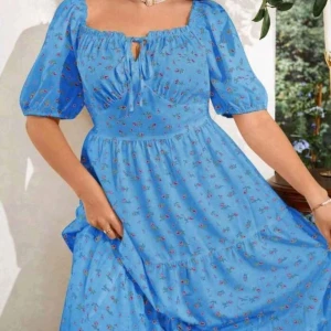 Blå blommig klänning med puffärmar - Superfin blå klänning med småblommigt mönster och puffiga kortärmar. Klänningen har en söt knytning vid halsen och volang i kjolen. Perfekt för sommarens alla tillfällen! Köpta på shein men är väldigt stort i storleken.  Passar från 1 Xl- 2Xl