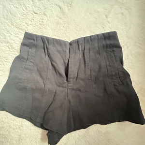 Svarta shorts  - Svarta kostym byx shorts liknande med  normal passform. Gjorda med diskreta fickor fram och bak. Perfekta för varma dagar och enkla att matcha med olika toppar.