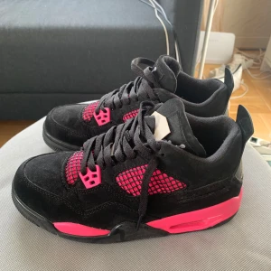Svarta och rosa Nike Air Jordans - Säljer ett par svarta Nike Air Jordans med rosa detaljer. Skorna har svarta skosnören, meshpaneler och rosa inslag på sula, nät och snörningsdetaljer. Klassisk Jumpman-logga på plösen. Perfekta för dig som vill sticka ut med färg. 