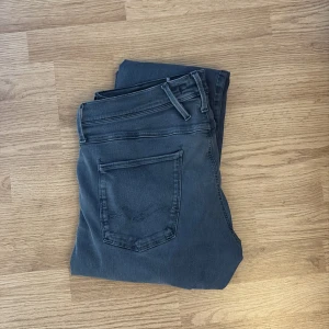 Replay grå jeansbyxor herr - Säljer ett par grå jeans från Replay med klassisk femficksdesign och dragkedja. Byxorna har normal passform och raka ben. Perfekta för dig som gillar stilrena och bekväma jeans till vardags.