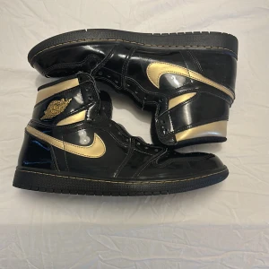 Nike Air Jordan 1 Retro High OG Black/Gold - Säljer ett par Nike Air Jordan 1 Retro High OG i svart och guld med glansig finish Strl 44.5. Väldigt bra skick, knappt använda! Skorna säljs utan skosnören, Behövs skosnören på ca 185 cm, säljs utan låda (borttappad) Därav det låga priset! 🤩💸 Nypris ca 2400 kr! Priset är förhandlingsbart!