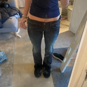 Mörkblå lågmidjade jeans - Säljer ett par mörkblå jeans med låg midja och klassisk femficksdesign. Jeansen har en rak passform och subtila slitningar framtill för en avslappnad look. Perfekta till vardags och lätta att matcha med olika toppar.