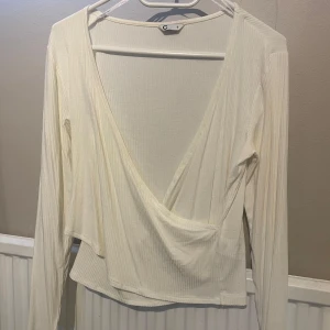 Vit omlottopp från Cubus - Säljer en vit omlottopp med djup v-ringning från Cubus i storlek S. Aldrig använd🤍