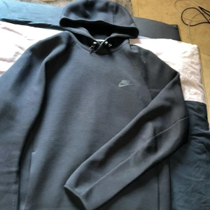 Svarta mjukisbyxor från Nike - Svarta mjukisbyxor från Nike med dragsko i midjan och två dragkedjeförsedda fickor framtill. Byxorna har en sportig look och Nike-logga på låret. Perfekta för en avslappnad stil.