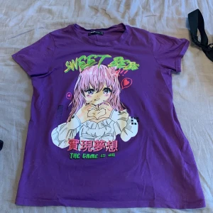 Lila anime t-shirt från FB Sister - Säljer en lila t-shirt från FB Sister med färgglatt anime-tryck och texten 'Sweet Bebe' på bröstet. T-shirten har korta ärmar och rund halsringning. Perfekt för dig som gillar japansk stil och vill sticka ut med en unik design!💜