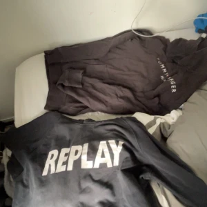 Svart hoodie från Tommy Hilfiger även flertalet märkeskläder - Svart hoodie från Tommy Hilfiger med logga på bröstet och ficka framtill. Klassisk huva och långa ärmar. Perfekt för en avslappnad stil.