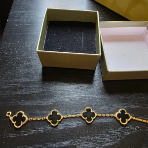 Armband Fyrklöver  - Guldfärgad och svart. 5 st fyrklöverlänkar. Kommer med originalbox