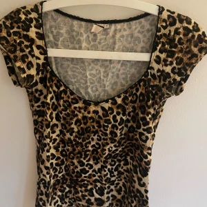 Leopardmönstad topp - Säljer en kort, tight topp från Nelly med leopardmönster. Toppen har korta ärmar och djup v-ringning. Säljer pga att jag inte använder den. Hör av er för fler bilder💘💘