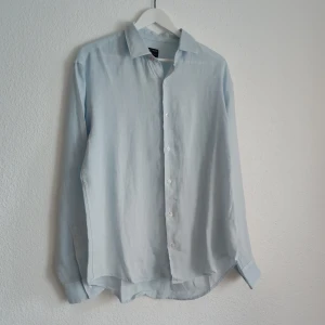 Ljusblå skjorta från Gerry St Tropez - Säljer en stilren ljusblå skjorta från Gerry St Tropez i storlek XL. Skjortan har klassisk krage, långa ärmar och knäppning framtill. Perfekt för dig som gillar en enkel och tidlös look.