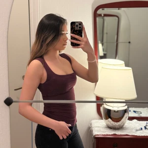 Mörkröd ribbad linnetopp - Säljer en mörkröd ribbad linnetopp med breda axelband och rundad halsringning. Toppen är tight och passar perfekt till jeans eller kjol. Enkel och stilren design som är lätt att matcha. Köpt ifrån BikBok i storlek XS. I helt nytt skick