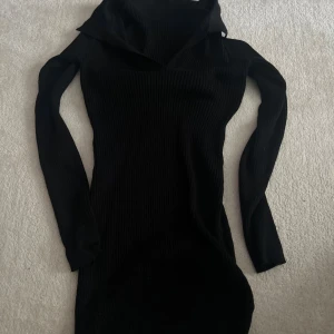 Svart ribbad långärmad klänning - Säljers en svart, tight ribbad klänning med lång ärm och hög krage. Klänningen har en kroppsnära passform och är perfekt för dig som gillar en stilren look.
