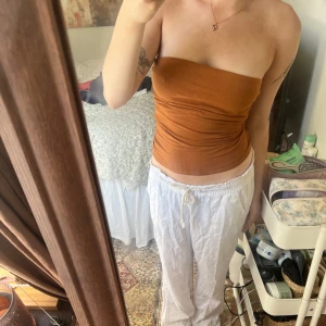 Brandgul tubtopp från Amisu🧡 - Säljer en snygg brun tubtopp. Toppen är axelbandslös och sitter tight mot kroppen, perfekt för varma dagar eller som lager under andra plagg. Står st S men jag säger att den passar Xs också då den sitter lite för thight på mig🧡🥹Den är så vacker och perfekt nu till vår/sommar 