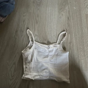 Beige ribbad linnetopp - Säljer en enkel och stilren beige ribbad linnetopp med smala axelband. Perfekt att matcha med jeans eller kjol för en avslappnad look.