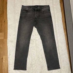 Jack Jones jeans - Säljer ett par grå jeansbyxor med klassisk femficksdesign.Modell slim/glenn men skulle säga att dom inte är jätte slim men fortfarande den stilen ochperfekta för dig som gillar en stilren look