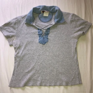 Grå topp med denimkrage från Grass Raggs - Säljer en grå pikétröja från Grass Raggs med korta ärmar och unik denimkrage. (Har en liten håll på baksidan som man ser i sista bilden)