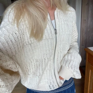 Vit stickad bomberjacka från Zara - Säljer en vit/beige stickad bomberjacka från Zara med coolt hålmönster och dragkedja framtill. Nypris på 600kr, fortfarande i nyskick! Perfekt som både jacka och kofta😋😋 (säljer även kjolen💓💓)