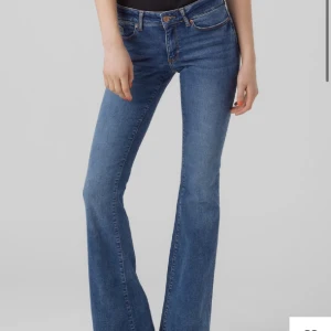 Blå jeansbyxor - Ett par blå jeansbyxor med låg midja och bootcut-stil. Byxorna har en knapp och dragkedja framtill samt fickor både fram och bak.