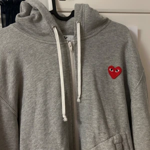 Cdg zip hoodie grå - Säljer nu denna feta Cdf zip hoodie🙌! Den är väldigt stil ren med ett sytt hjärta på bröstet. Den passar alla och är i perfekt skick. Ny pris ligger runt 3000kr💸 Om det finns några funderingar är det bara att fråga🦫 Kan såklart gå ner i pris vid snabb affär (max nån hundralapp)! Mvh William. Är ej hemma vid tillfället så är ändå bilden jag har men ifall kan säkert fixa mer ifall det önskas🙌👍.