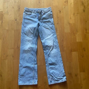 Ljusblå jeans från Kappahl, stl 152 - Snygga ljusblå jeans från Kappahl i rak modell med klassiska fem fickor och coola ficklock med knapp bak. Jeansen har normal midja och är tillverkade i mjukt bomullsdenim. Perfekta för en avslappnad och trendig look.