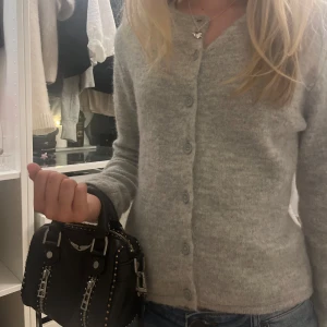 Ljusgrå stickad kofta med knappar - Supermjuk och mysig ljusgrå stickad kofta med knappar hela vägen framtill. Klassisk modell med lång ärm och enkel, stilren look som passar till jeans eller kjol. Perfekt för lager-på-lager och chill dagar. Premium quality 