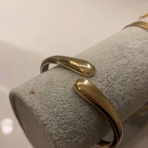 Guldigt armband  - Snyggt armband i guldig färg med en stilren, modern design. På andra bilden så snys det att armbanet inniut ifrån ör rostigt samr har slitage därav priset.